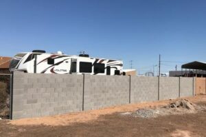 A view of a fence with a motorhome parked in the background.