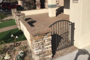 A brick wall with a gate and stone pillars.