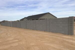 A concrete wall with a house in the background.