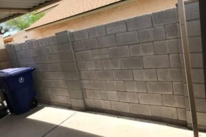 A man standing next to a wall with cement blocks.