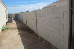 A concrete block wall with a fence around it.