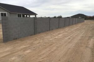 A concrete fence is shown with houses in the background.