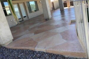 A patio with a stone floor and cement steps.