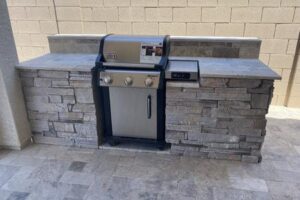 A grill sitting on top of a stone wall.