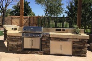 A grill and an outdoor kitchen with a stone wall.