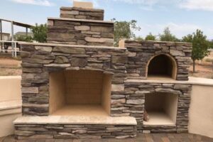 A stone fireplace with two ovens in it.