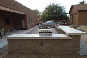 A patio with a grill and fire pit in it