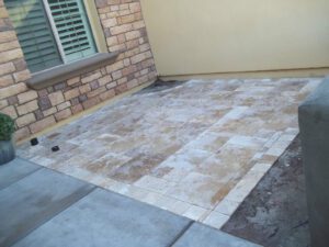 A patio with a brick wall and concrete floor.