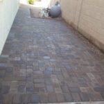 A brick walkway with a cement floor and wall.