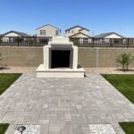 A memorial with a large stone wall and a brick walkway.