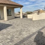 A patio with pavers and a large wall.