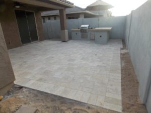 A patio with an outdoor grill and a large wall.