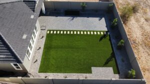 A backyard with a lawn and concrete wall.