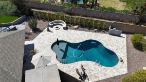 A pool with an umbrella and chairs in the middle of it.