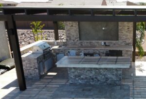 A large outdoor grill and television area with stone walls.