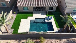 A backyard with an outdoor pool and patio furniture.