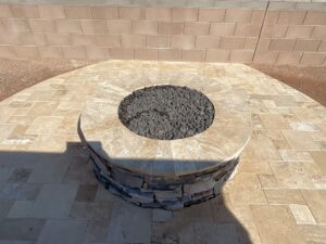 A fire pit with stone surround and tile wall.