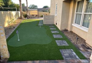 A backyard with a putting green and a brick path.