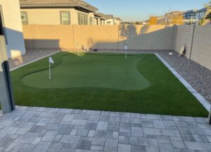 A backyard with a putting green and pavers.