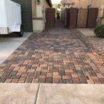 A driveway with brick pavers and concrete