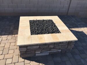 A fire pit with black rocks on top of it.