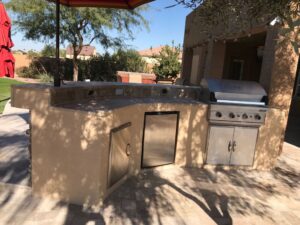 A grill and an outdoor kitchen in the middle of a patio.