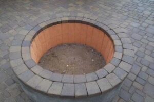 A fire pit with brick sides and a circular opening.