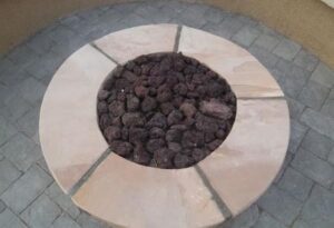 A fire pit with rocks in it sitting on top of a brick patio.