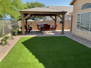 A backyard with an outdoor grill and lawn.