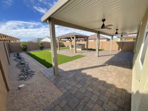 A patio with an umbrella and grass in the middle of it