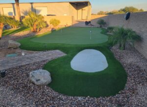 A backyard with a putting green and sand trap.