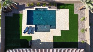 A pool with an umbrella and chairs on the side of it.